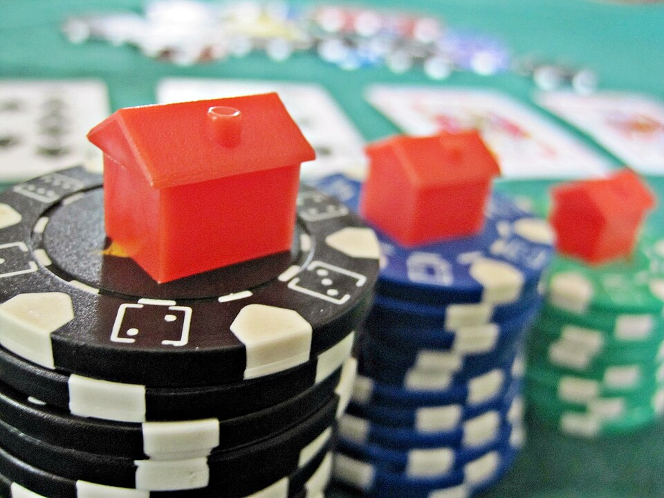 Stack of colorful casino chips and Monopoly houses representing bankroll strategy