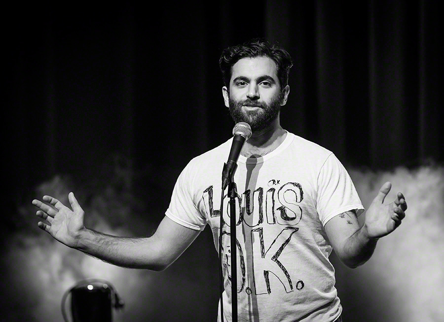 Stand-up comedian performing on stage with microphone at comedy festival